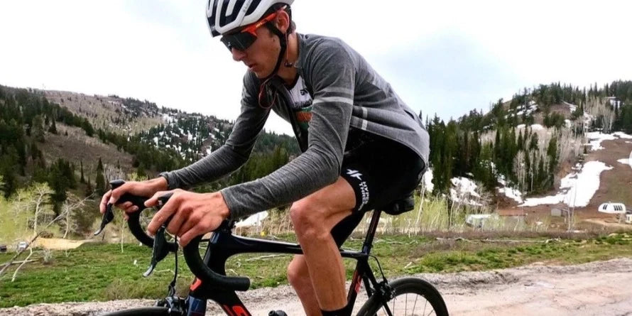 Cyclist wearing black bib shorts with shoulder straps and padded chamois, demonstrating proper fit and positioning on road bike.
